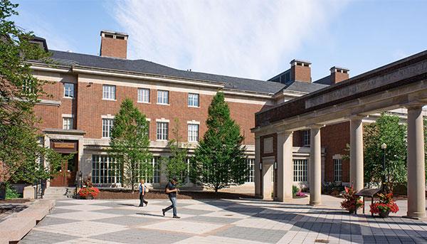 Exterior of courtyard in front of brick building and students walking through